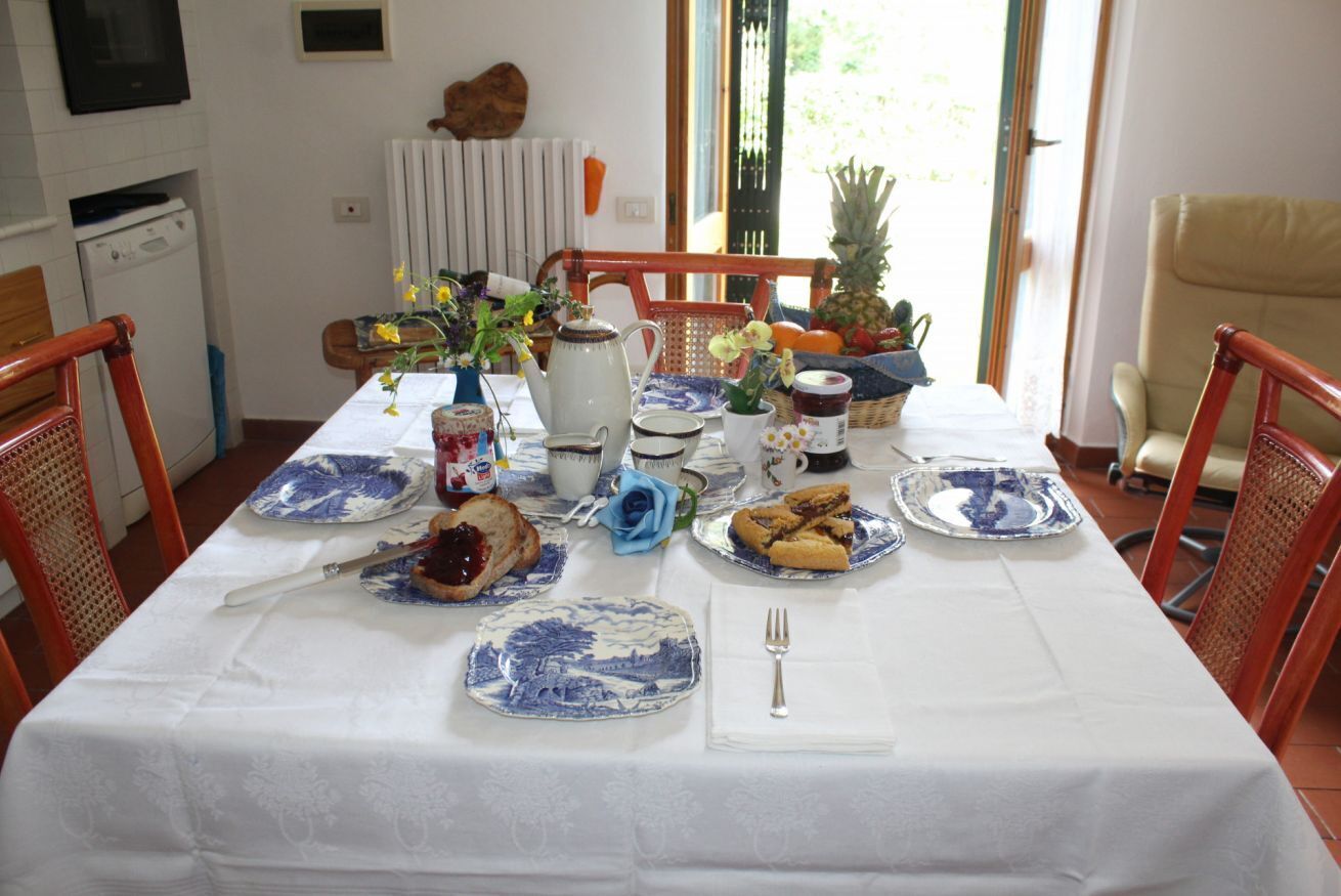 Une table à manger dressée avec des assiettes, un pichet, un vase de fleurs et divers aliments.