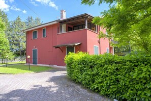 Ein rotes, zweistöckiges Haus mit einer Veranda, einem Schornstein und einem gepflasterten Einfahrt.