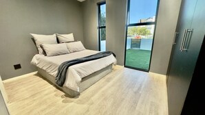 Ein Schlafzimmer mit Bett, Kleiderschrank und einem großen Fenster.