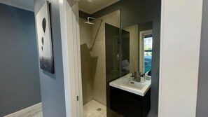 A modern bathroom with a glass shower enclosure, a white sink, and a large mirror.