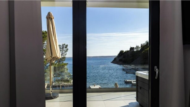 A balcony with a view of the sea, a sun umbrella, and a stone bench. - Villa Lucija Velebit (Barić Draga)