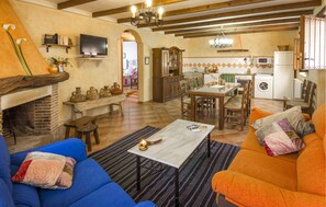 A cozy living room with a fireplace, a television, and a dining area with a table and chairs. - Beautiful home in Laroya with outdoor swimming pool (Laroya)