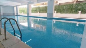 An indoor swimming pool with clear water, a tiled floor, and a metal ladder. - Riara One Residence- Gateway (Nairobi)