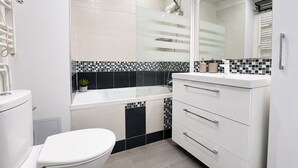 A modern bathroom with a toilet, a sink, a mirror, and a shower. - Luxueux Appartement au 16e  (Paris)