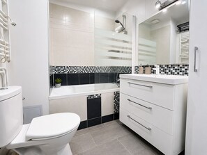 A modern bathroom with a toilet, a sink, a mirror, and a shower.