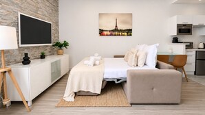 A modern bedroom with a bed, bedside table, TV, and a cityscape painting. - Luxueux Appartement au 16e  (Paris)