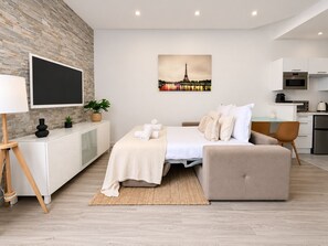 A modern bedroom with a bed, bedside table, TV, and a cityscape painting.