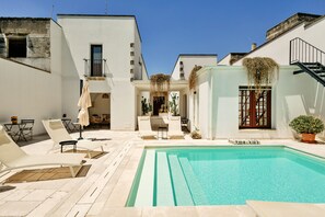 A poolside area with lounge chairs, a small table, and a staircase leading to an upper level. - La Corte Bella (Leverano)