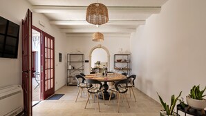 Een eetruimte met een ronde tafel, stoelen en een hanglamp.