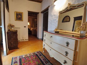 A room with a wooden dresser, a mirror, a patterned rug, and a doorway leading to another room. - I Tre Camini by Interhome (Montieri)