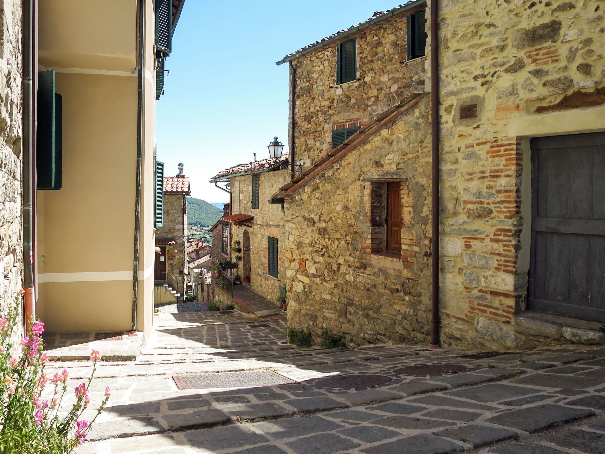 Une ruelle pavée bordée de bâtiments traditionnels, avec une petite fenêtre et une porte.
