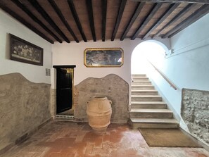 A staircase with a rustic stone wall, a wooden door, and a large barrel. - I Tre Camini by Interhome (Montieri)