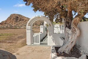 Entrada arqueada blanca a una propiedad, con un letrero que dice 'IRINI STUDIOS' y un número de contacto.