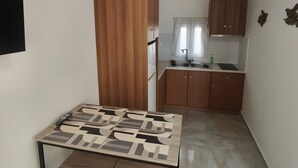 Una cocina compacta con armarios de madera, una mesa de comedor con estampado geométrico y un techo con vigas a la vista.