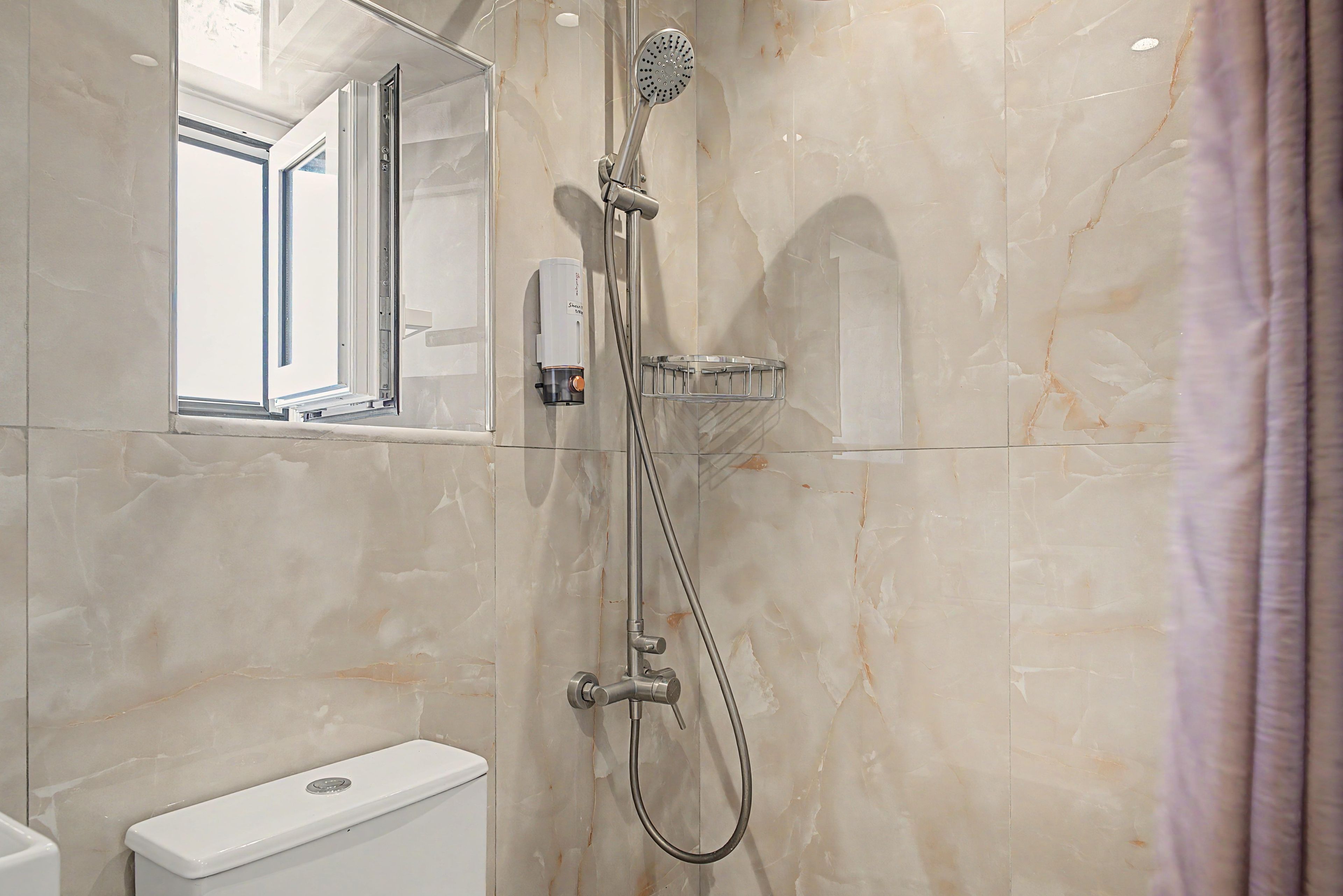 Un baño con ducha, inodoro y ventana.