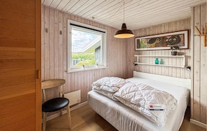 A small, cozy room with wooden walls, a single bed with white bedding, a window with a view of greenery, a hanging pendant light, and a shelf with a plant. - Gorgeous home in Hejls with WiFi (Hejls)