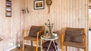 Een kamer met houten lambrisering, twee houten stoelen, een kleine tafel en een lijst met een afbeelding.