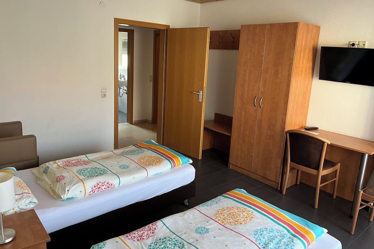 Habitación de hotel con dos camas, un escritorio, un armario y un televisor.
