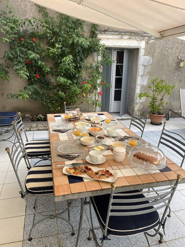 Une table à manger installée à l’extérieur, avec des chaises, une variété de plats et une plante en pot.