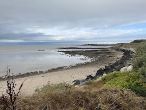 Un paysage côtier caractérisé par une plage de sable, une côte rocheuse et une végétation clairsemée.