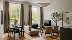 Una sala de estar moderna con comedor, ventanas amplias, un televisor de pantalla plana y una planta decorativa.
