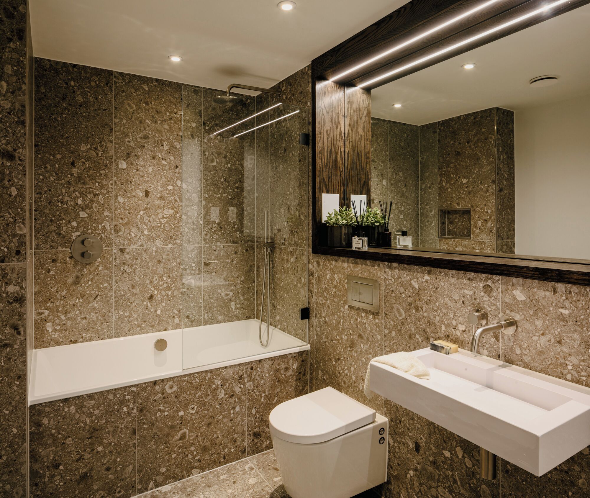 Een moderne badkamer met een douchecabine van glas, een vrijstaand bad en een wastafel op een voetstuk.