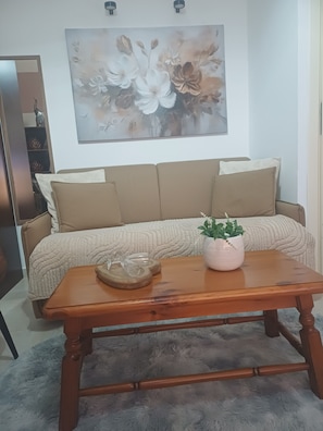 Ein Wohnzimmer mit einer Couch, einem Couchtisch, einem Gemälde und einer Zimmerpflanze.