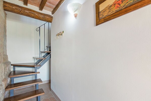 Un escalier avec des marches en bois et des rampes en métal, un mur blanc avec un luminaire et un tableau encadré.