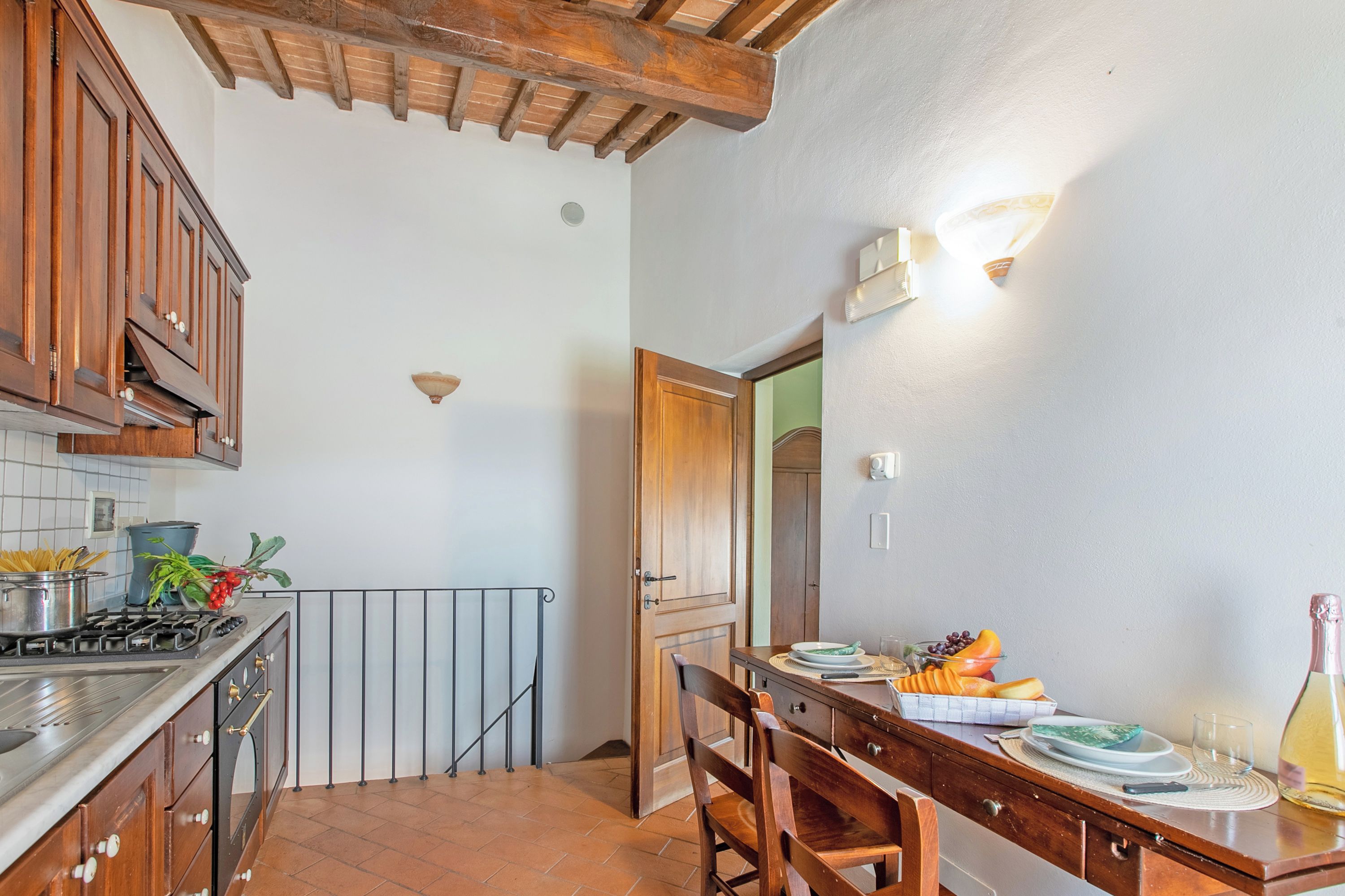 A kitchen with wooden cabinets, a stove, and a dining table set with plates and a bottle.