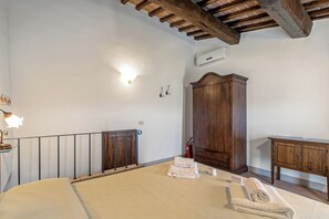 Une chambre à coucher comprenant un lit, une armoire en bois, une petite table de chevet, une lampe fixée au mur et un extincteur.
