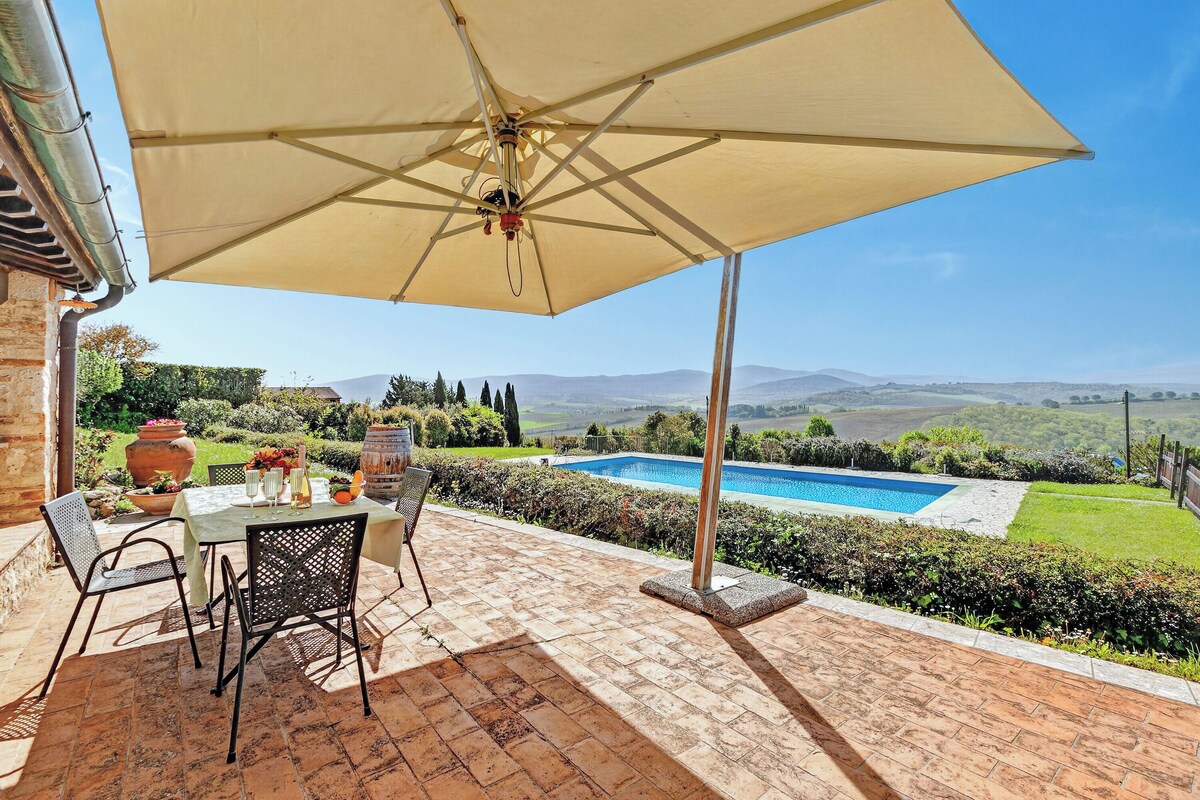 An outdoor patio with a table, chairs, and a large umbrella.