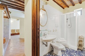 Ein Badezimmer mit Dusche, zwei Waschbecken, einem Bidet und einer Toilette.