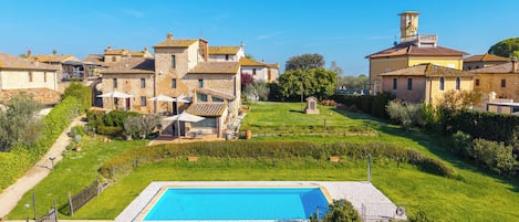 A residential area with a swimming pool, stone buildings, and a tower.