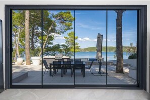 Ein moderner Essbereich im Freien mit Blick auf das Meer und Bäume.
