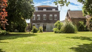 A two-story brick building with a large glass entrance, surrounded by a well-maintained lawn and trees. - Villa cosy proche Valenciennes (La Sentinelle)