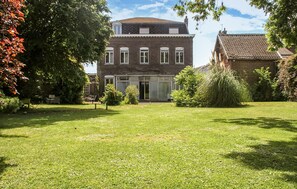 A two-story brick building with a large glass entrance, surrounded by a well-maintained lawn and trees. - Villa cosy proche Valenciennes (La Sentinelle)