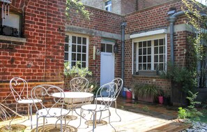 A brick building with a patio area featuring a round table and four chairs. - Villa cosy proche Valenciennes (La Sentinelle)