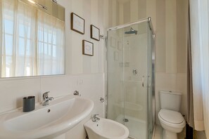 Ein Badezimmer mit Duschkabine, Waschbecken, Bidet und Toilette.