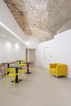 Un interior moderno con techo de piedra, un área de comedor con sillas amarillas y un sofá amarillo.