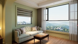 A living room with a sofa, a coffee table, and a large window with a view of a cityscape. - Dalabiang Hotel (Xuan Huong - Da Lat)