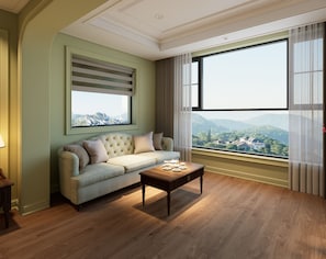 Una sala de estar con un sofá, una mesa de centro y un ventanal con vista a un paisaje urbano.