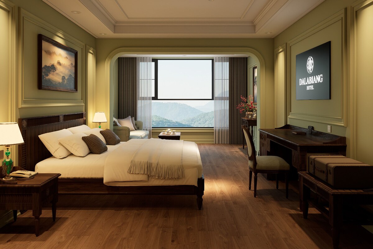 Quarto de hotel com uma cama grande, uma escrivaninha, uma cadeira, uma mesa de cabeceira, uma luminária, uma TV e vista para as montanhas.