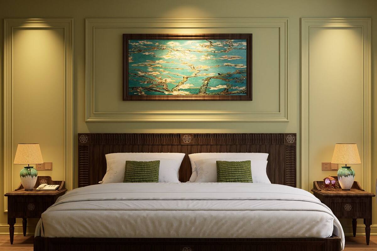 A large bed with a wooden headboard, two nightstands with lamps, and a painting above the bed.