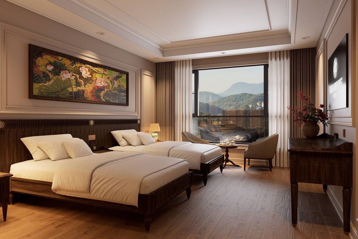 A hotel room with a large bed, a smaller bed, a desk, a chair, and a large window with a view of mountains.