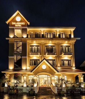 A multi-story hotel with a prominent entrance, a staircase leading to the main entrance, and a balcony on the upper floors. - Dalabiang Hotel (Xuan Huong - Da Lat)
