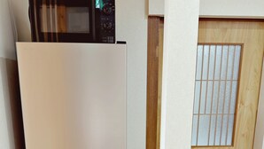 A kitchen with a refrigerator, microwave, and wooden door. - Dc Sakura Hotel - Tenjin Beppu (Osaka)