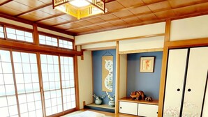 A traditional Japanese room with tatami flooring, two tatami beds, a shoji screen, a wooden ceiling, and a small shelf with decorative items. - Dc Sakura Hotel - Tenjin Beppu (Osaka)