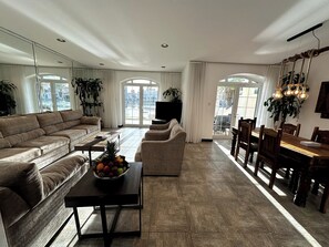 A spacious living area with a sofa, dining table, and chairs, a fruit bowl on a coffee table, and a TV. -  Sunset Beach Resort for Entertainment (Eastern Province)