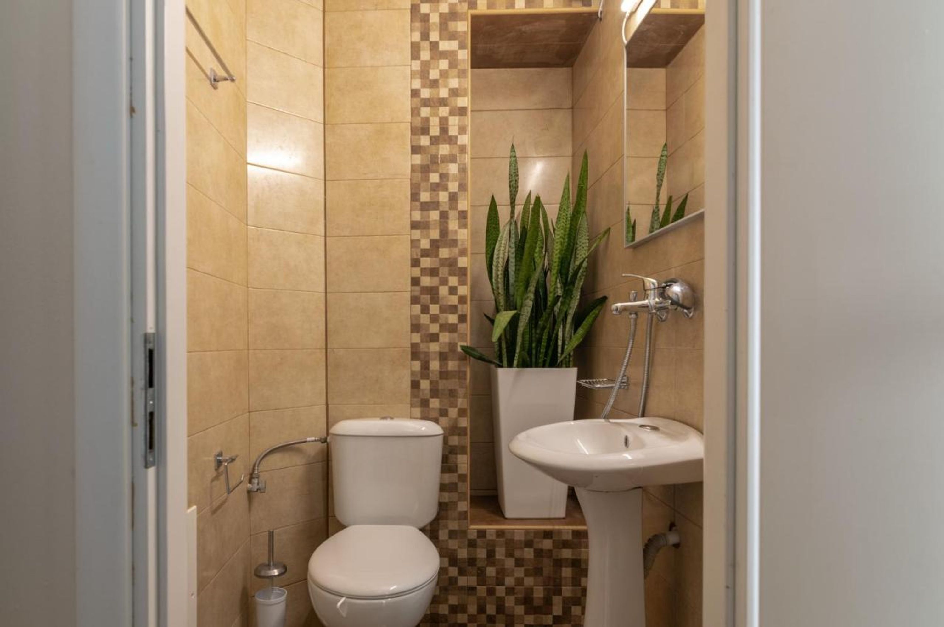 A bathroom with a toilet, sink, and a potted plant.