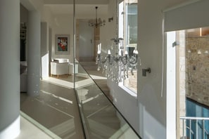 Ein modernes Interieur mit einer Glaskabine, einem Chandelier und einer Treppe, die zu einer weiteren Ebene führt.